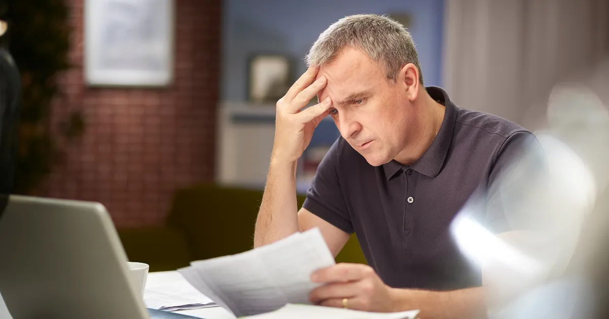 A stressed man looking at bills at a desk
