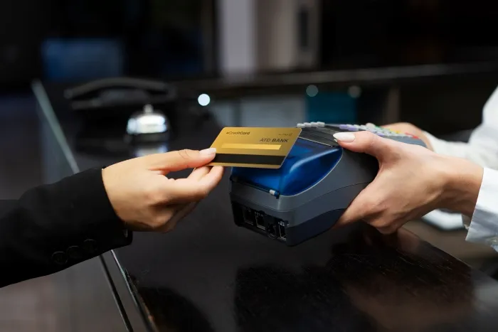 A person using a credit card to pay on a card reader terminal.