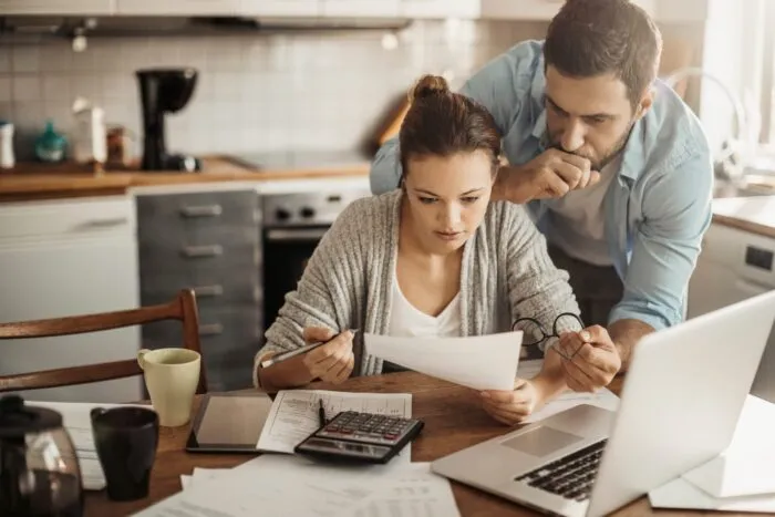 A couple reviewing bills and financial documents together at a table.